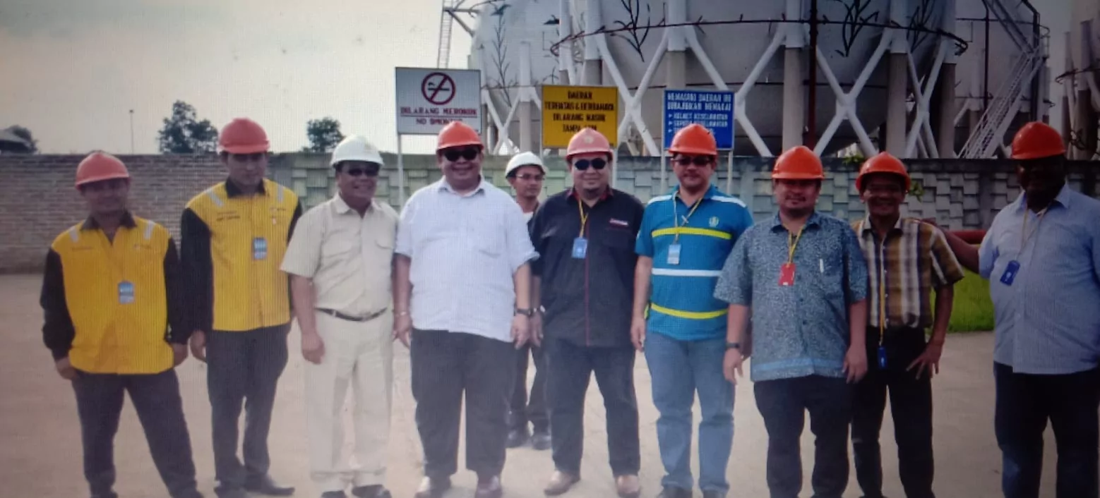 The Suria Crestway team with terminal staff in safety helmets in front of storage tanks