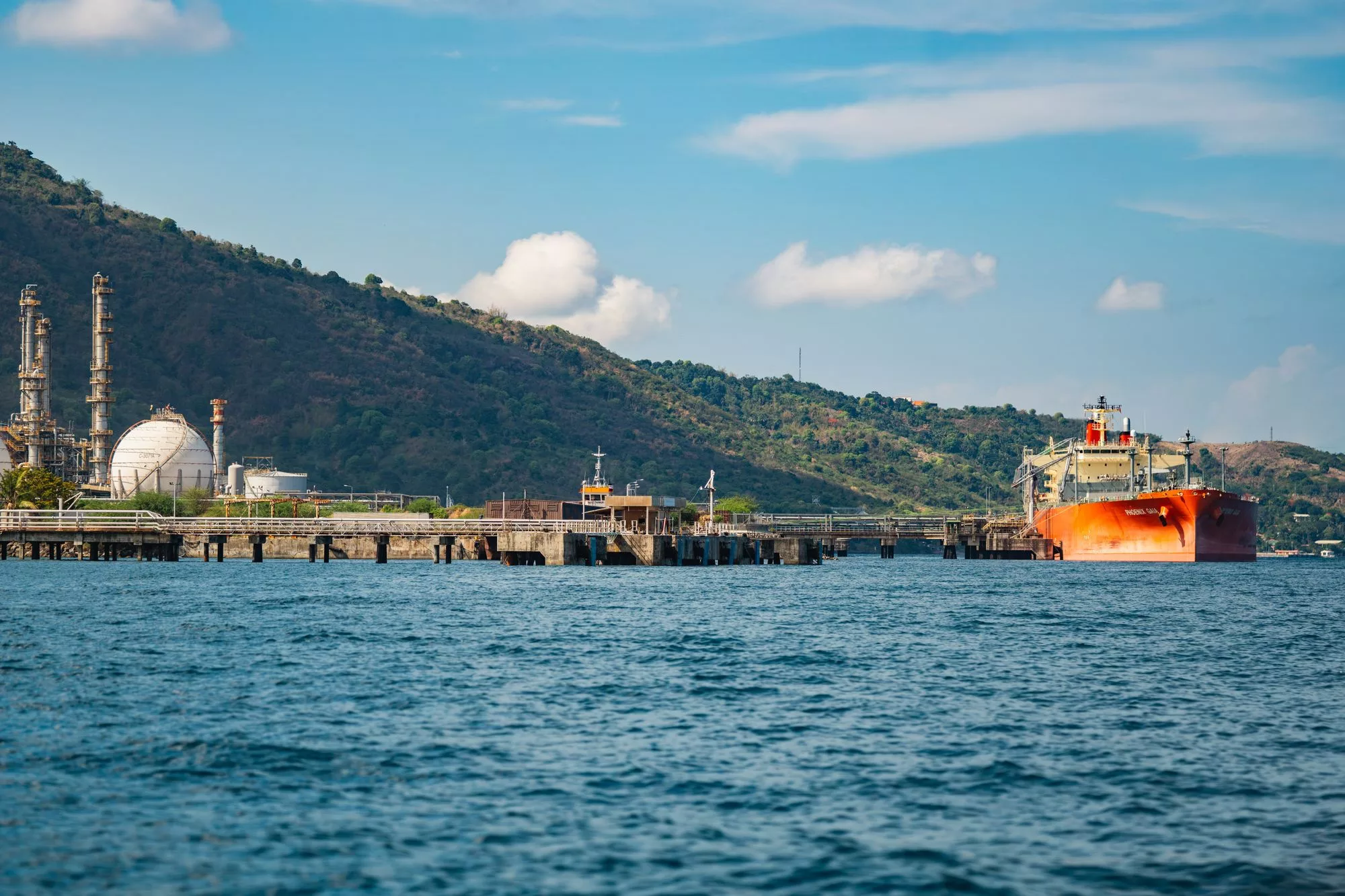 Tanker alongside a fuel terminal below a wooded headland