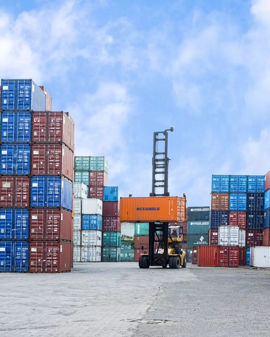 Reach stacker working a stacked container yard under a clear sky