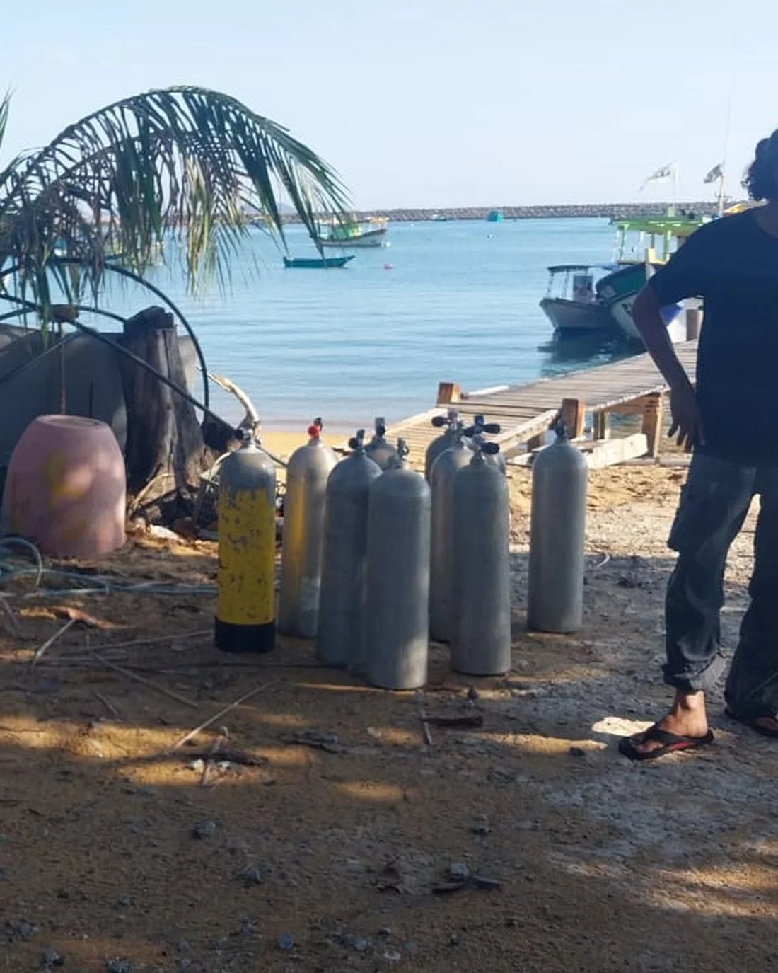 Dive cylinders and equipment staged on the beach beside the work boats