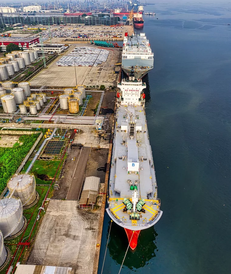 Product tanker alongside a tank farm with a support craft made fast