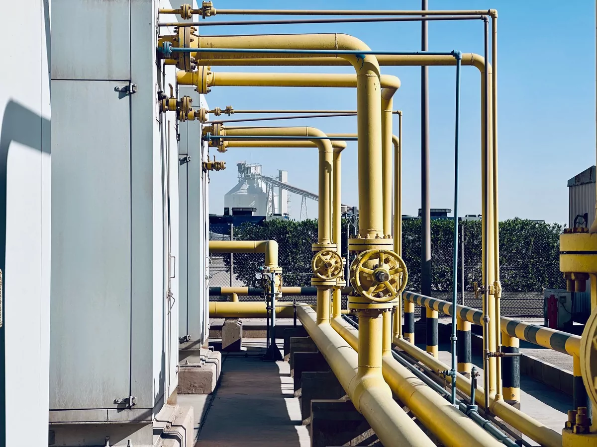 Painted process pipework and hand valves running along a plant walkway