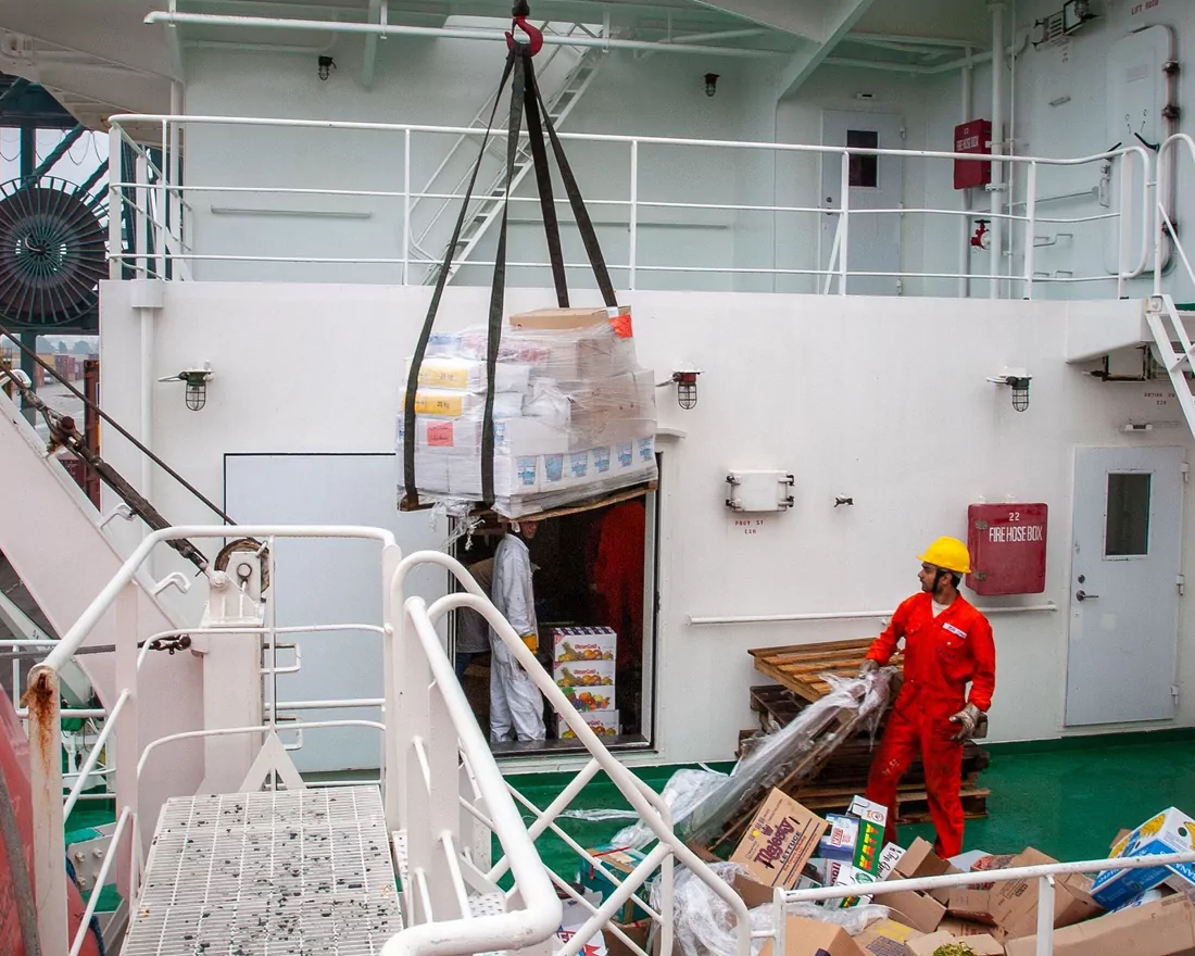 Deck crew taking a crane lift of supplies aboard a support vessel