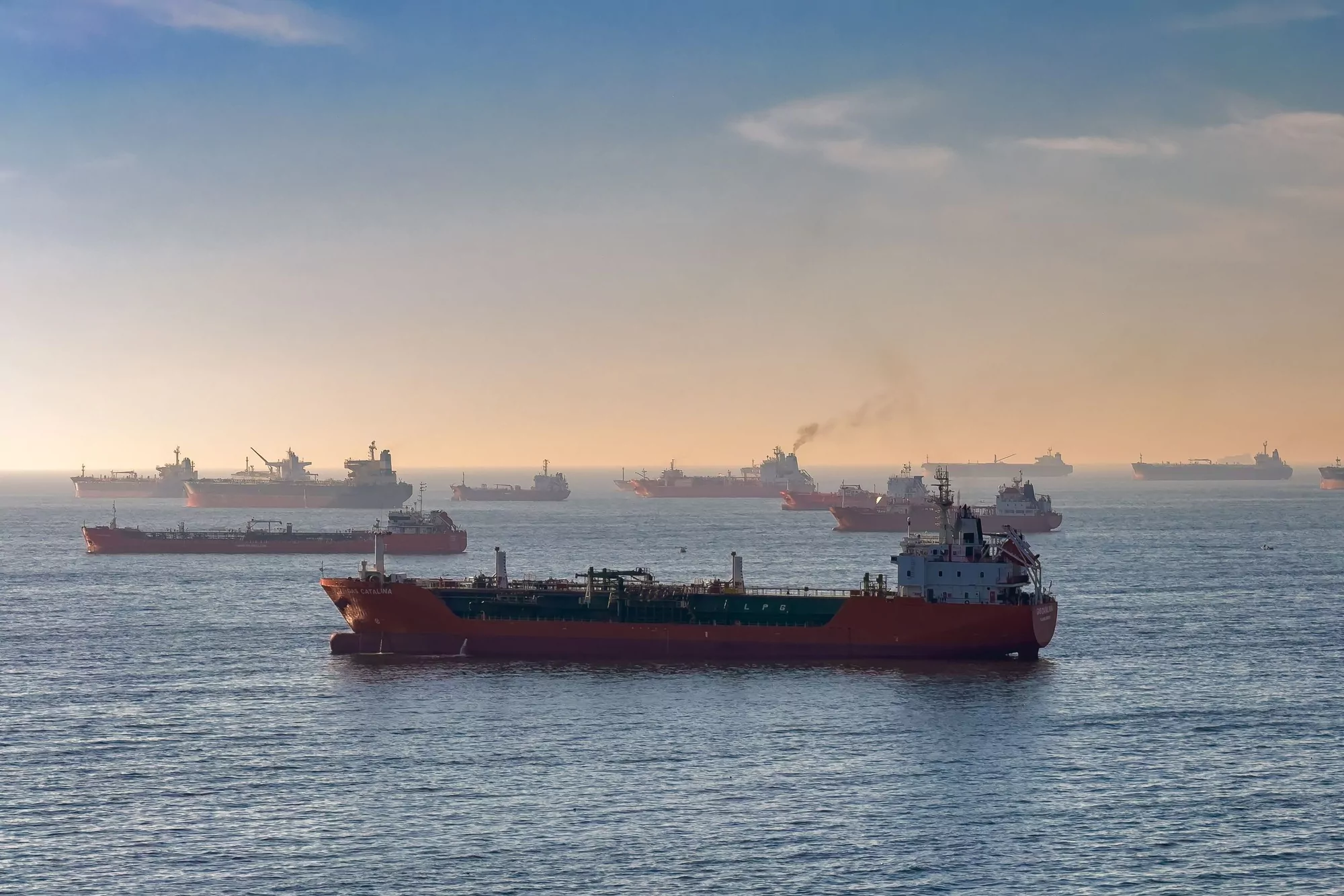 Tankers and bulk carriers lying at an offshore anchorage at first light