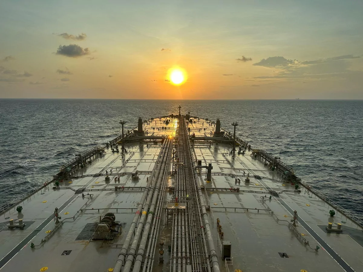 Cargo manifold and pipework running the length of a laden tanker's main deck at sunset