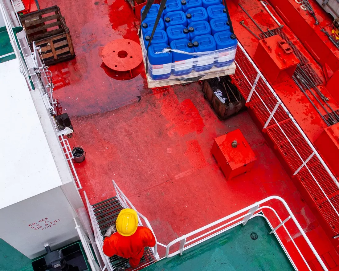 Ship's deck seen from above with crew taking a pallet of stores aboard