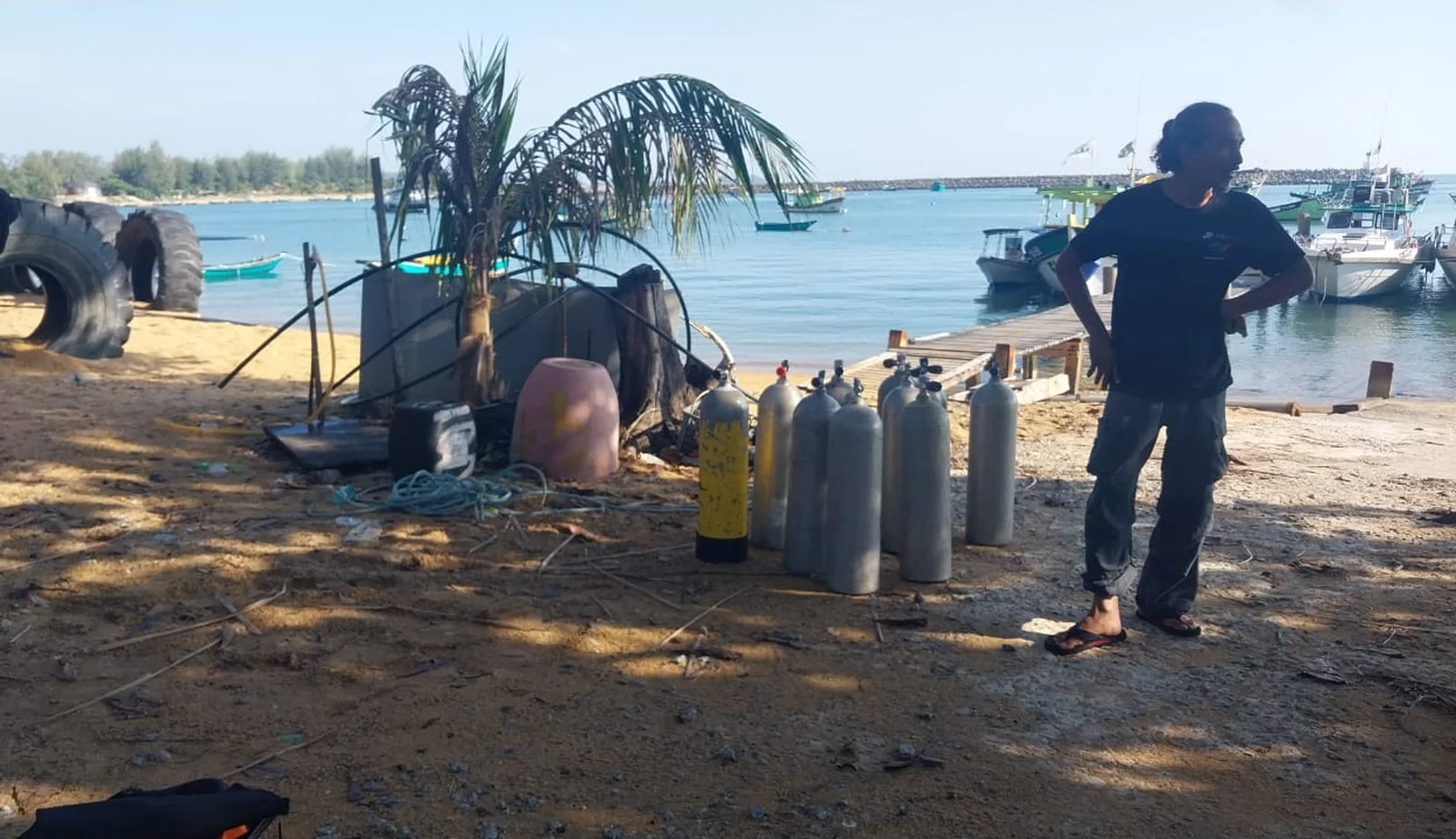 Dive cylinders and equipment staged on the beach beside the work boats